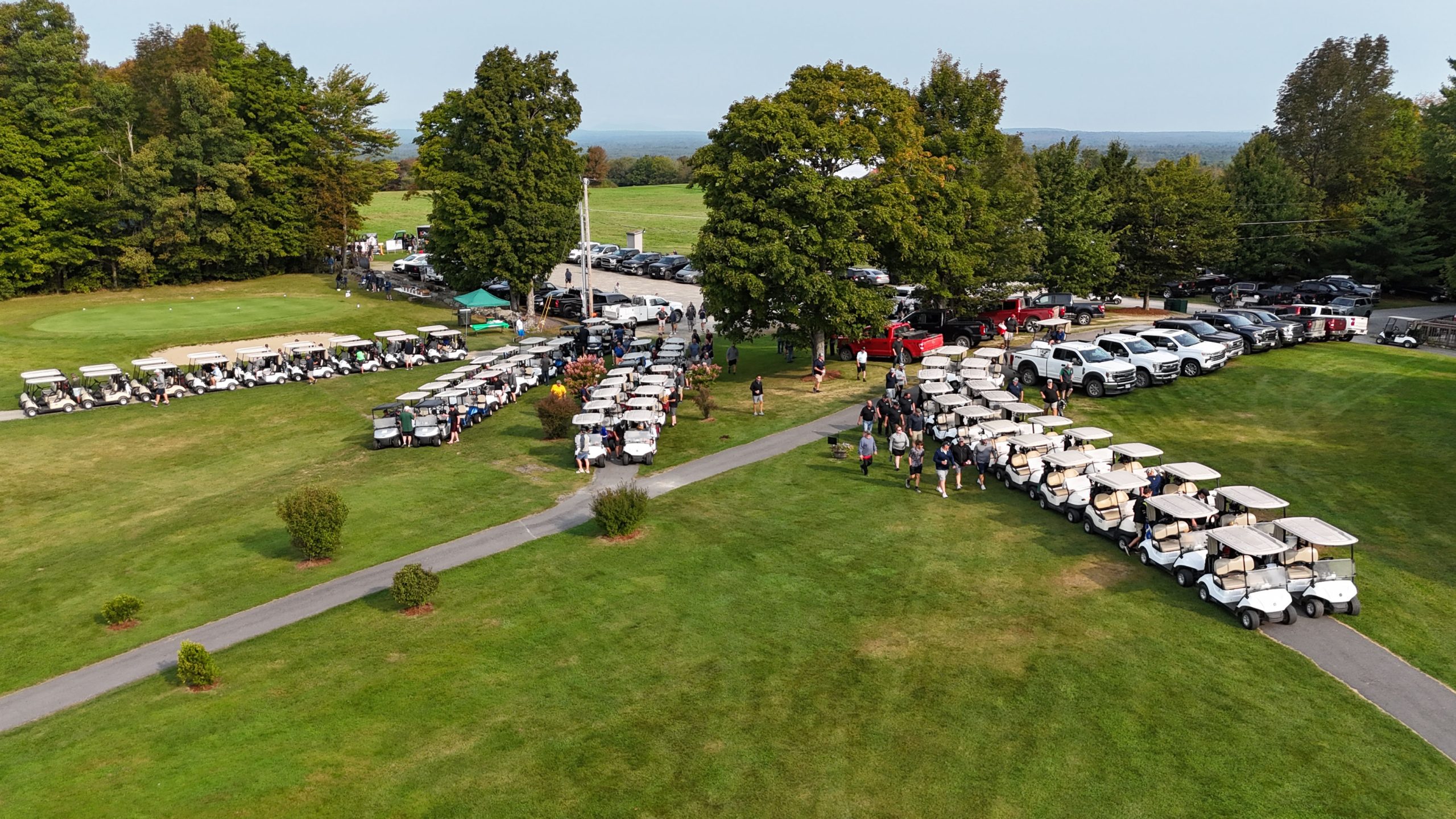 aerial photograph of people, vehicles, and golf carts at the JaTo Highlands Golf Course