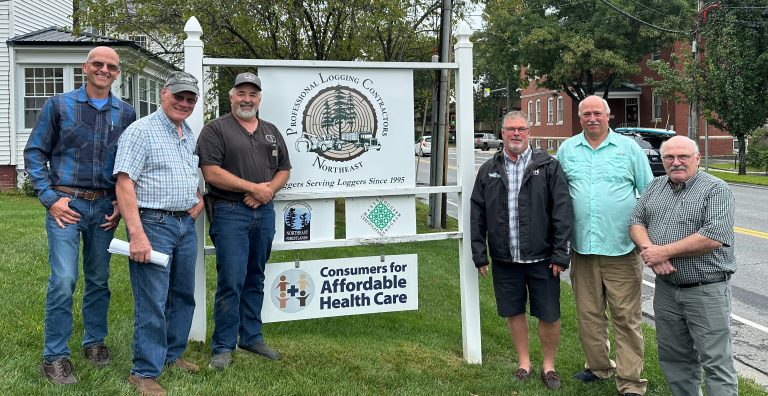 Photo of the PLC Executive committee standing in front of the Professional Logging Contractors of the Northeast sign. From left to right: Kurt Babineau, Duane Jordan, William Cole, Marc Greaney, Chuck Ames, and Andy Irish